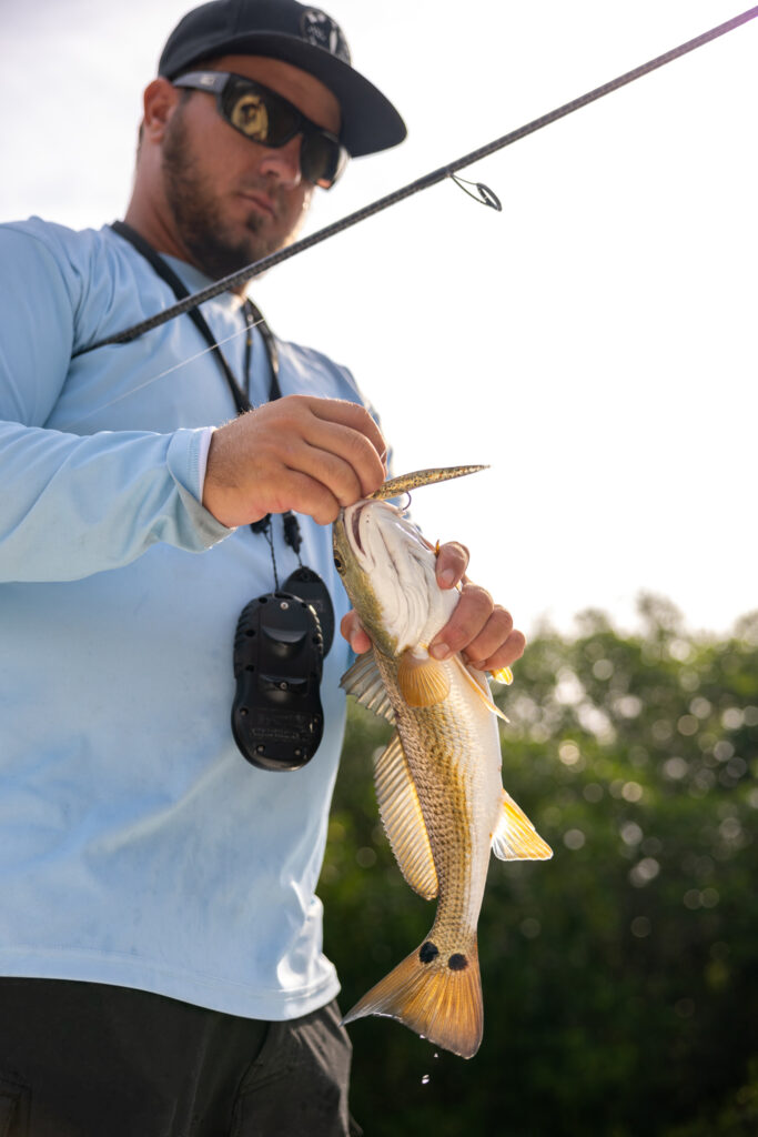 Captain Alex Hughey unhooking a redfish